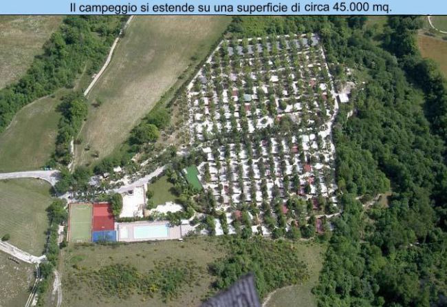Vista aerea di un campeggio con aree verdi, campi sportivi e una piscina.