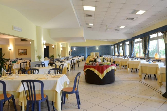 Ampia sala da pranzo con tavoli apparecchiati e sedie blu.