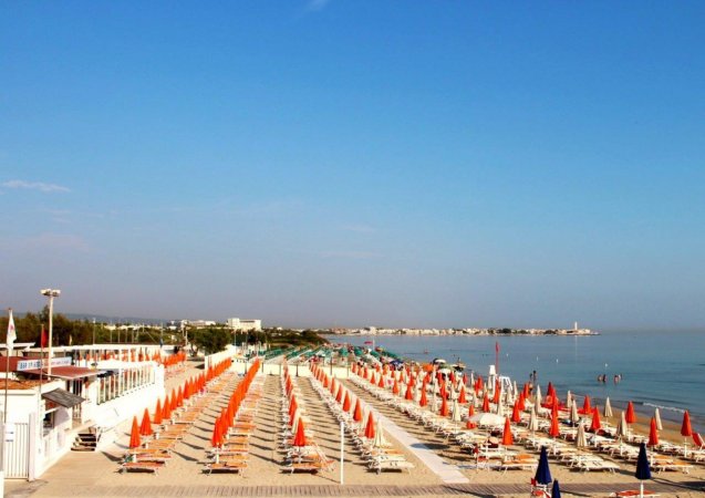Spiaggia con ombrelloni arancioni e mare calmo.
