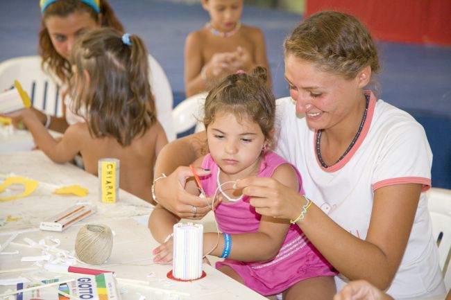 Bambina e adulta fanno lavoretti a un tavolo.