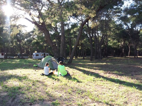 Due persone sedute davanti a una tenda in un bosco.