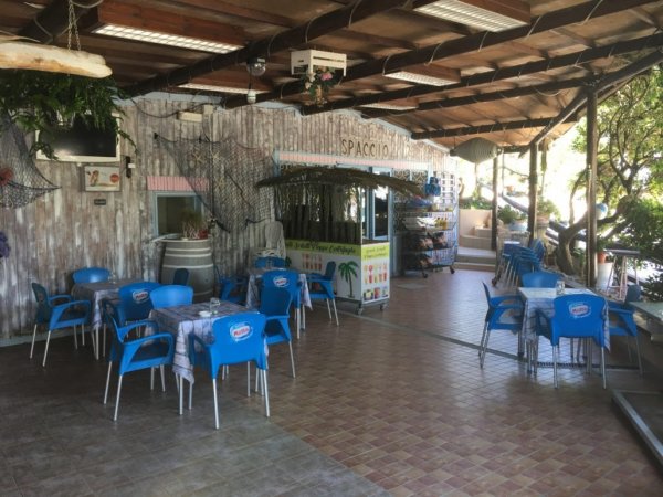 Sala esterna con tavoli e sedie blu.