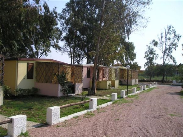 Bungalow gialli allineati lungo una strada sterrata in un'area verde.