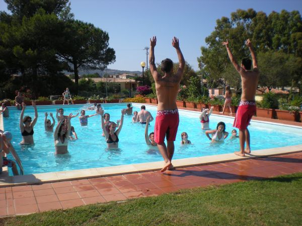 Persone in una piscina che seguono istruttori a bordo vasca.