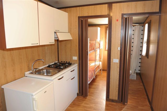 Cucina compatta con letto a castello in fondo.