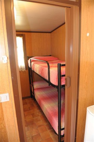 Letto a castello con coperte rosa in una stanza con pareti in legno chiaro.