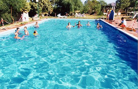 Piscina all'aperto con persone che nuotano e si rilassano intorno.
