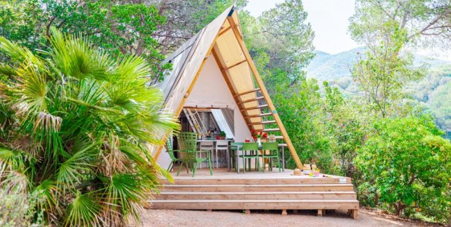 Tenda a forma di A immersa nella vegetazione.