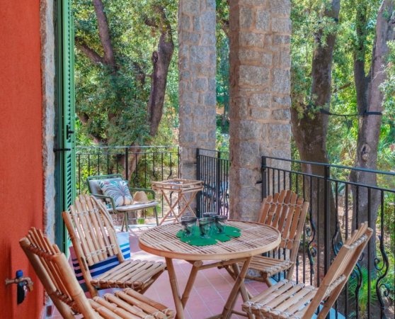 Balcone con sedie in legno e vista sul bosco.