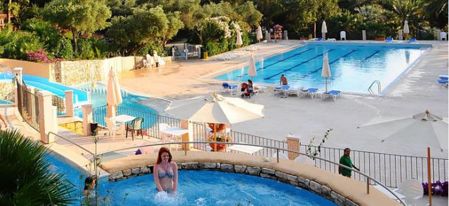 Piscina grande con sdraio e una piscina più piccola con persona.