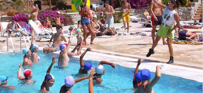 Una lezione di acquagym in piscina, con persone che seguono le istruzioni dell'istruttore.