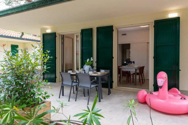 Terrazza con tavolo da pranzo e fenicottero gonfiabile rosa.