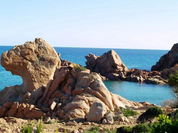 Massi di roccia scolpita affacciati su un mare blu.