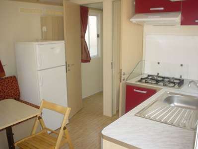 Cucina di un bungalow con fornelli, frigorifero e lavandino, arredamento semplice.