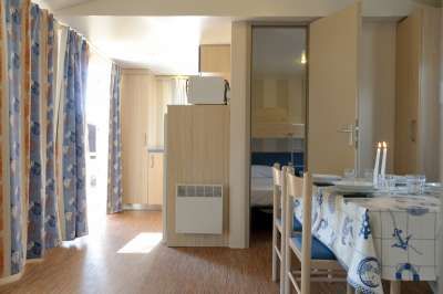 Interno di una casa vacanze con tavolo apparecchiato, sedie e tende a fiori.