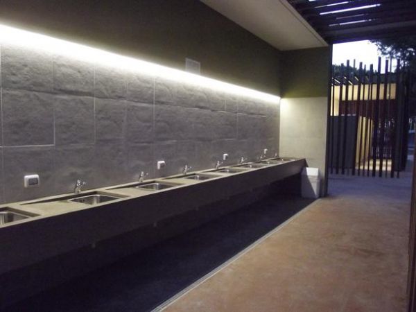 Lungo banco con lavandini in un'area illuminata.