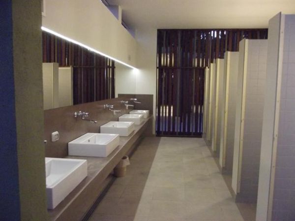 Bagno pubblico con lavandini moderni e cabine chiuse.