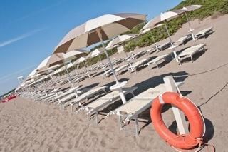 Spiaggia con lettini, ombrelloni e un salvagente arancione.
