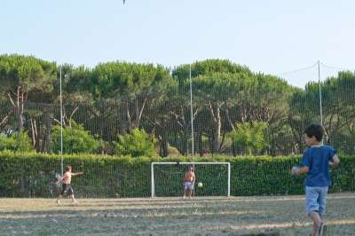 Bambini giocano a calcio all'aperto, con un bambino che entra in campo.