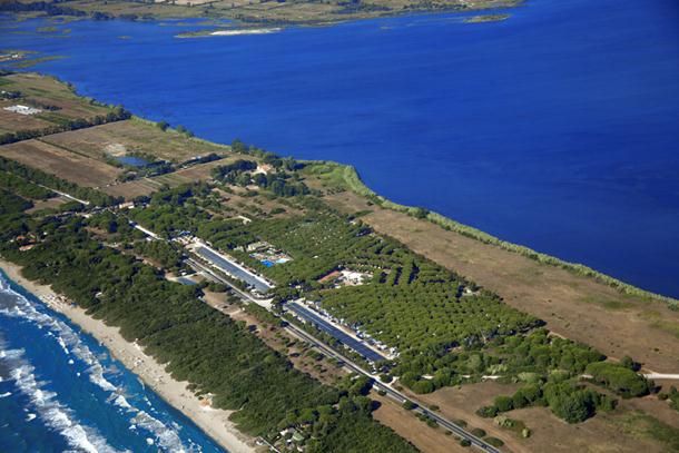 Vista dall'alto di una spiaggia con vegetazione e un'area sviluppata vicino al mare.