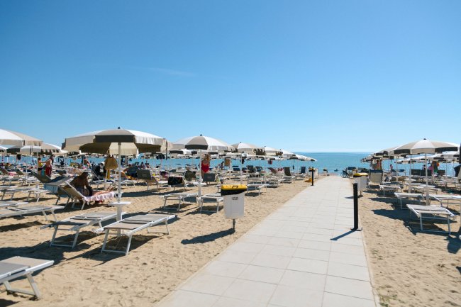 Spiaggia con ombrelloni bianchi e lettini.