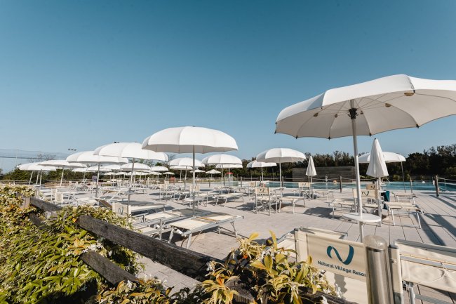 Lettini e ombrelloni bianchi su terrazza.