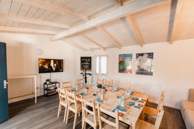 Sala con tavolo lungo e televisore.