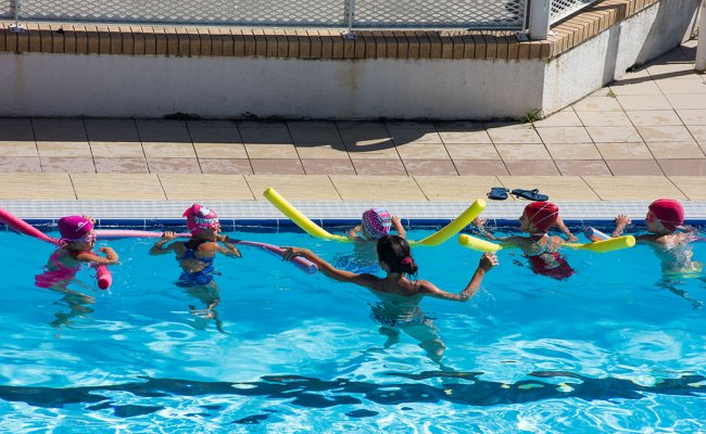 Bambini apprendono a nuotare in piscina.