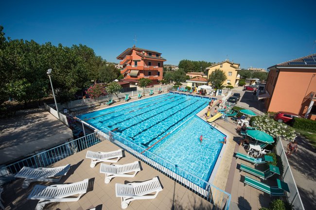 Piscina con sdraio e edifici circostanti.