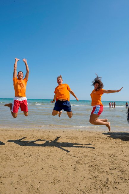 Tre persone saltano sorridenti sulla spiaggia.