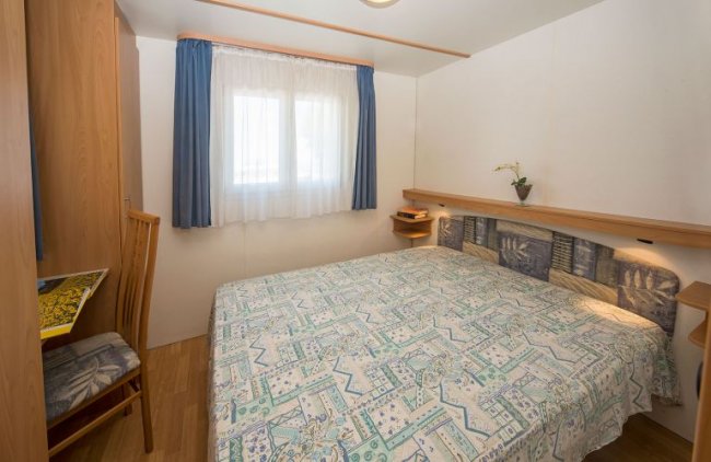 Stanza con letto matrimoniale e finestra con tende blu.