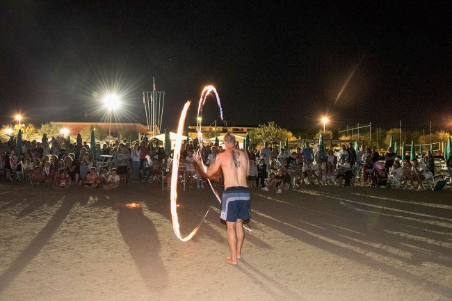 Esibizione di giocoleria col fuoco davanti a un pubblico di notte.