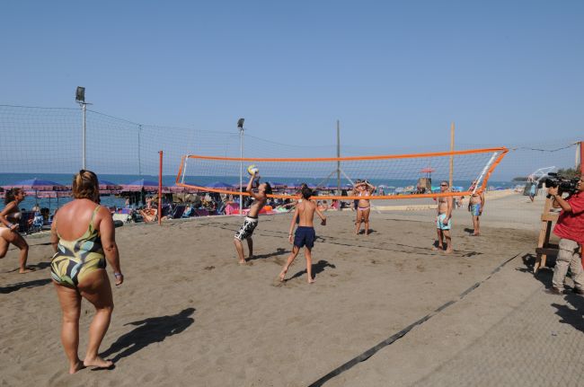 Persone giocano a beach volley sulla sabbia vicino al mare.