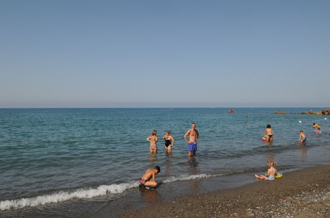 Persone giocano sulla riva del mare sotto un cielo limpido.