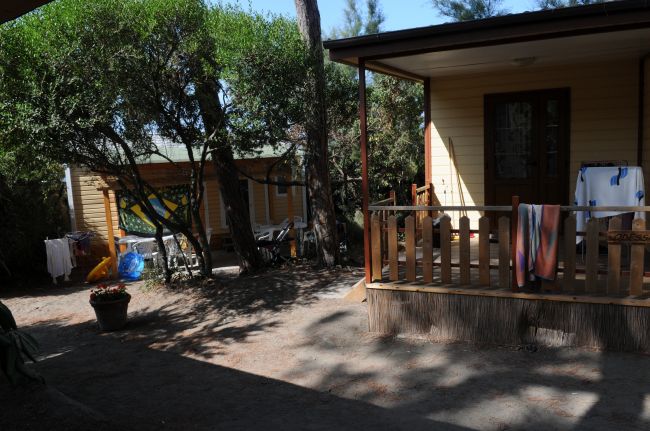 Veranda in legno con asciugamani, circondata da alberi.