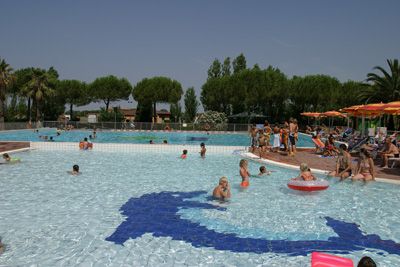 Piscina con bambini e ombrelloni arancioni.