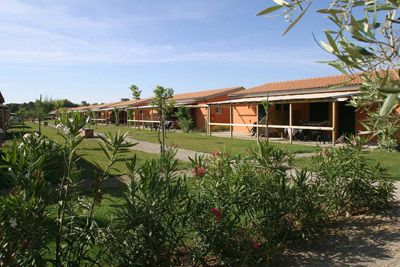 Bungalow allineati in un villaggio vacanze, con giardini curati e piante fiorite.