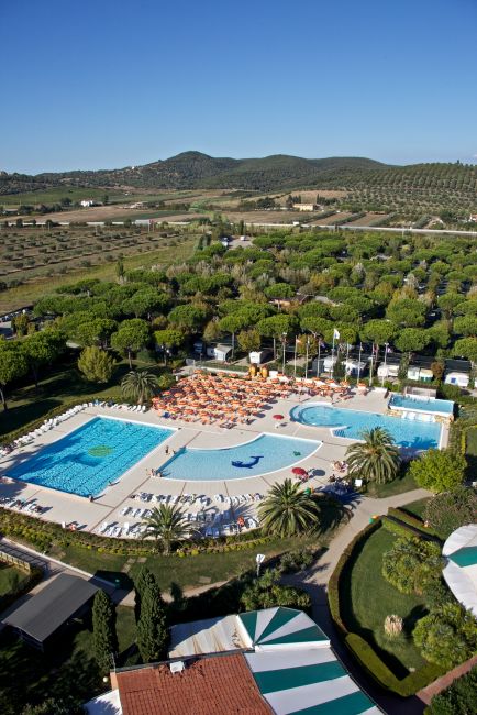 Vista aerea di un grande complesso con due piscine, ombrelloni arancioni e vegetazione rigogliosa.