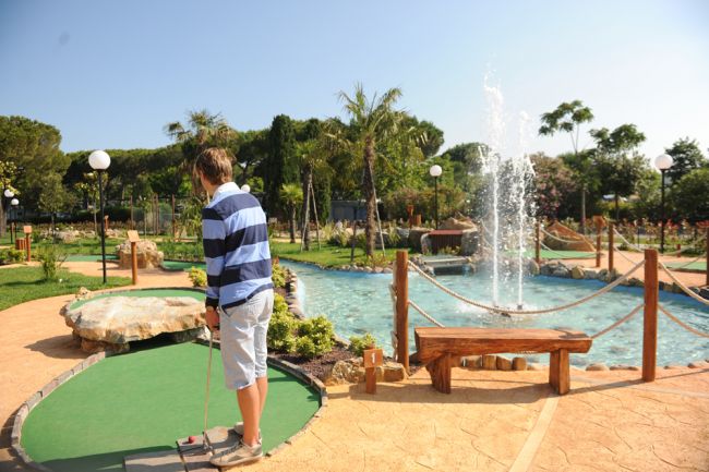 Ragazzo gioca a minigolf vicino a una fontana.