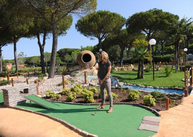 Donna gioca a minigolf in un parco verde.