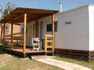 Veranda in legno di una casa mobile con sedia bianca.