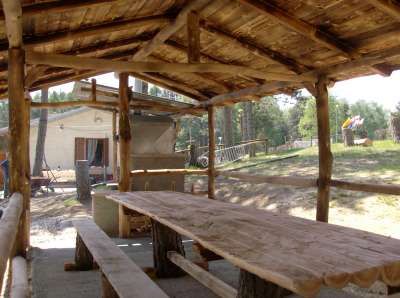 Tavolo e panche di legno sotto un pergolato all'aperto.