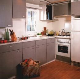 Cucina moderna con mobili grigi e elettrodomestici bianchi, parquet a terra.
