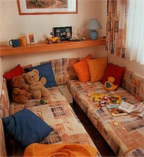 Due divani con cuscini colorati, peluche e giocattoli. Mensola con oggetti.