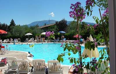 Piscina con lettini, fiori e montagne sullo sfondo.