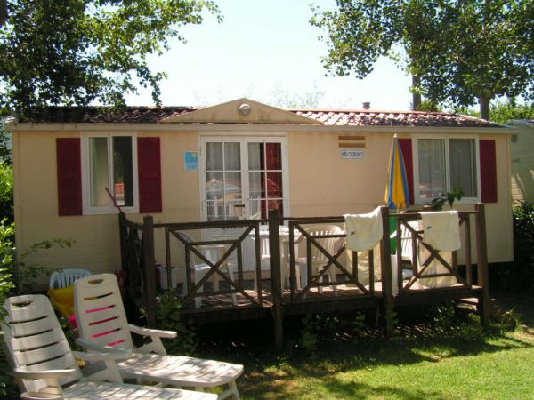 Una casa mobile con terrazza in legno, lettini e asciugamani appesi all'esterno.