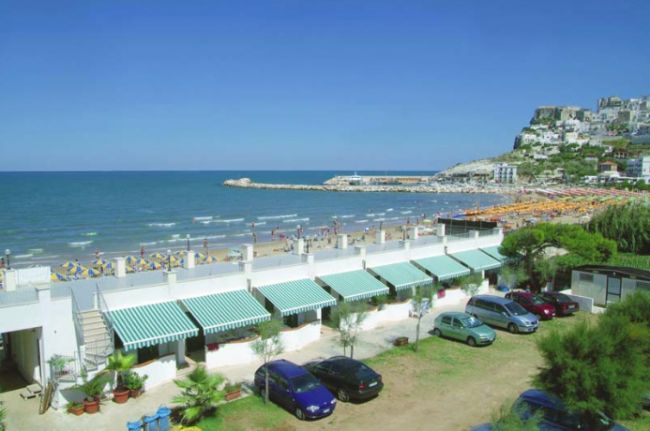 Spiaggia con mare, auto parcheggiate.