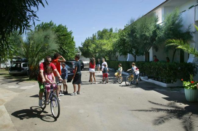 Persone in bici in un cortile alberato.