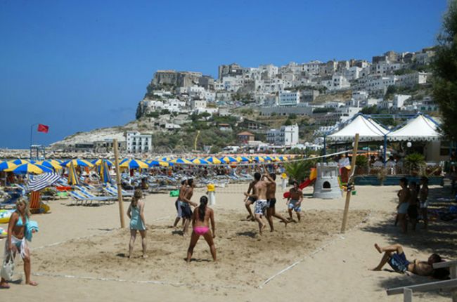 Spiaggia con persone che giocano a beach volley.