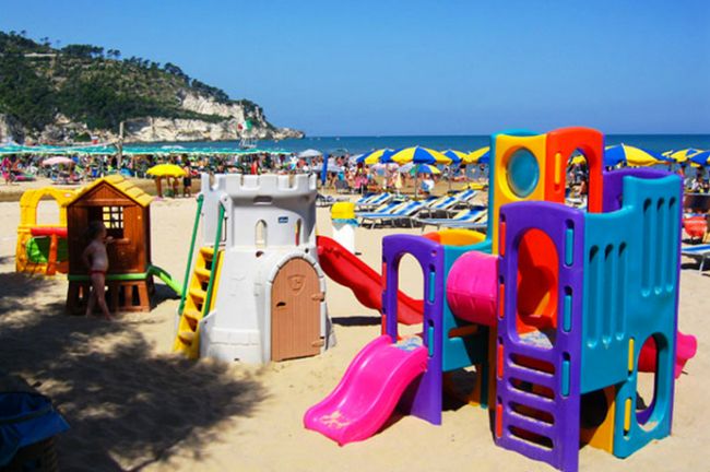 Area giochi per bambini sulla spiaggia, con scivoli colorati.